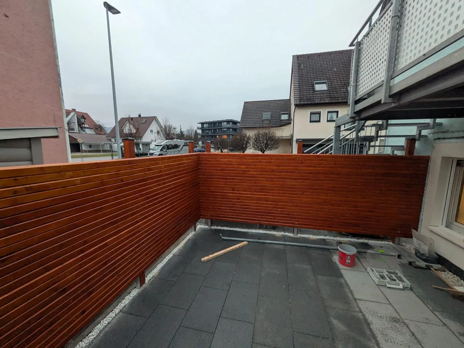 Holz-Sichtschutzzaun um eine Dachterrasse mit dunklen Platten