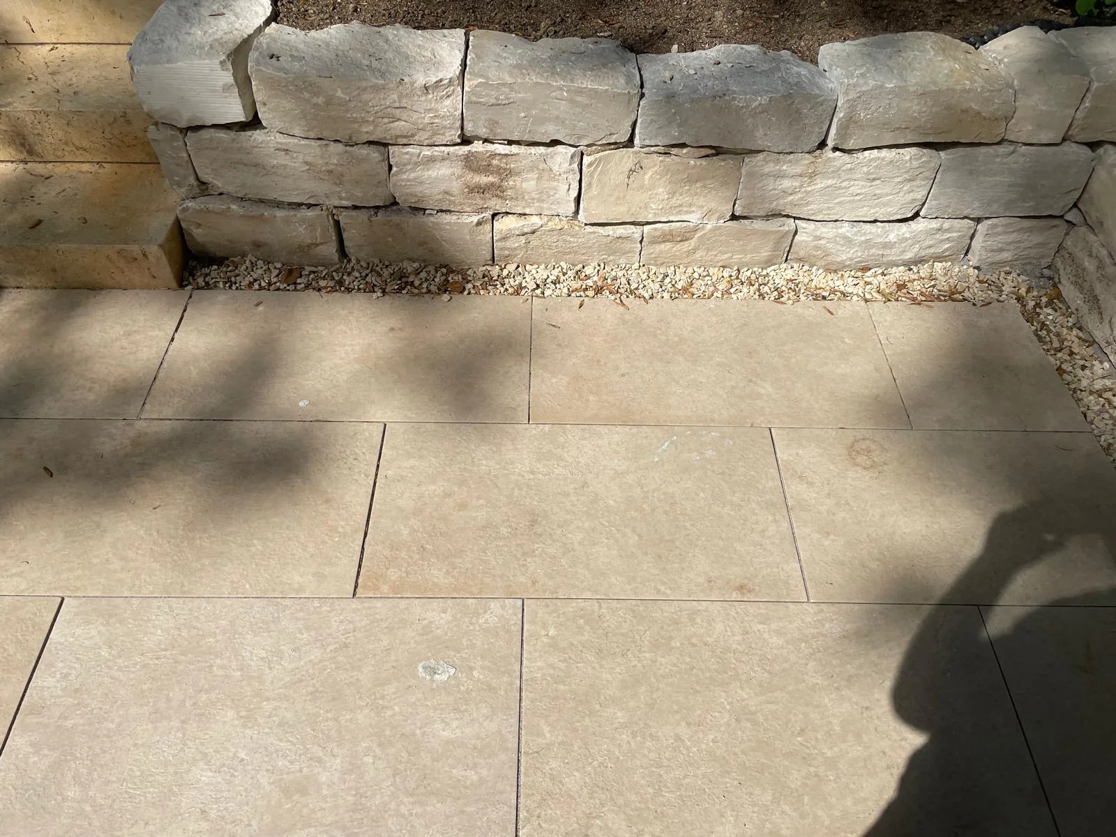 Terrasse aus großformatigen Natursteinplatten vor einer Natursteinmauer