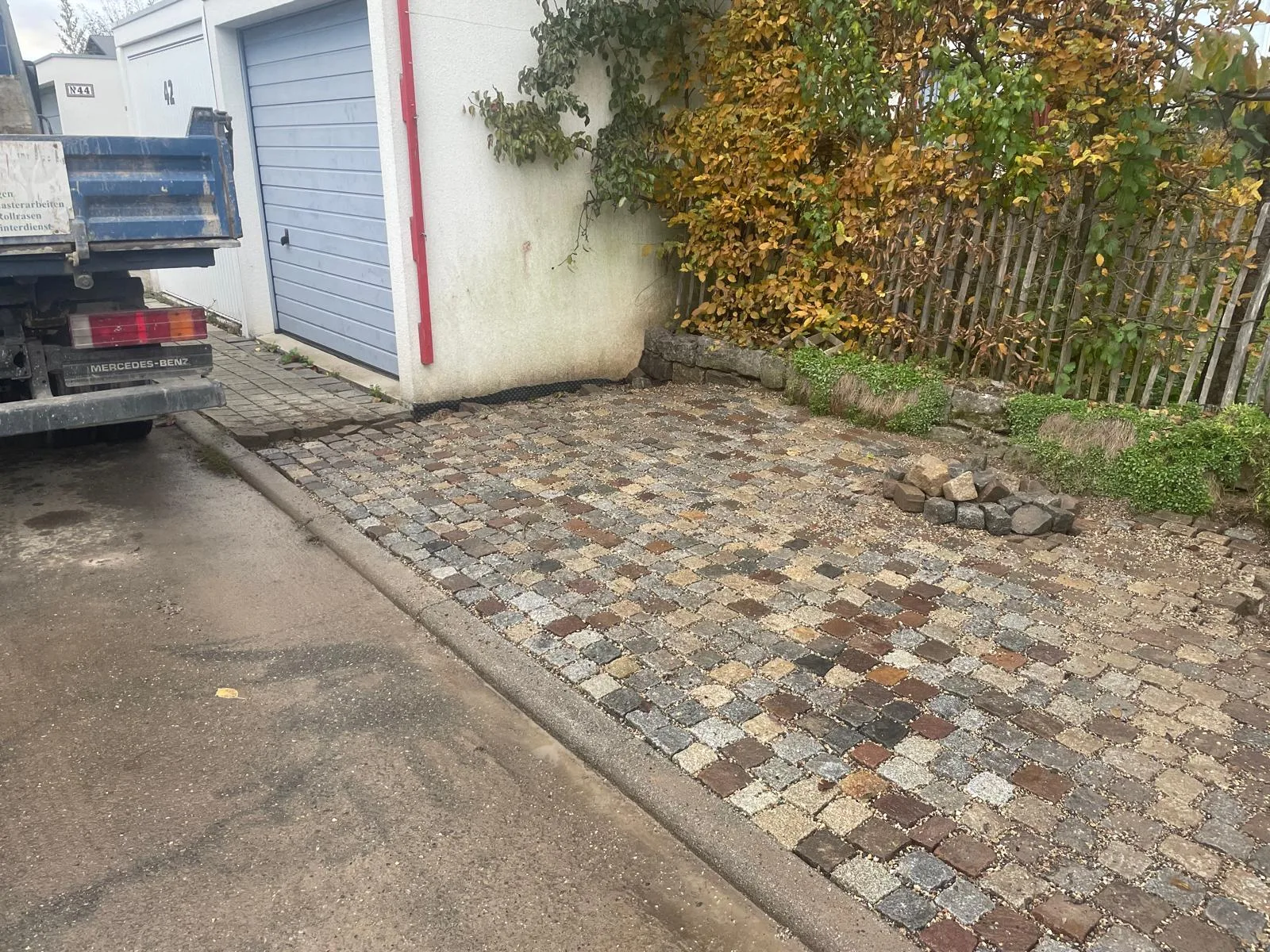 Mehrfarbiges Natursteinpflaster in einer Einfahrt neben einer Garage